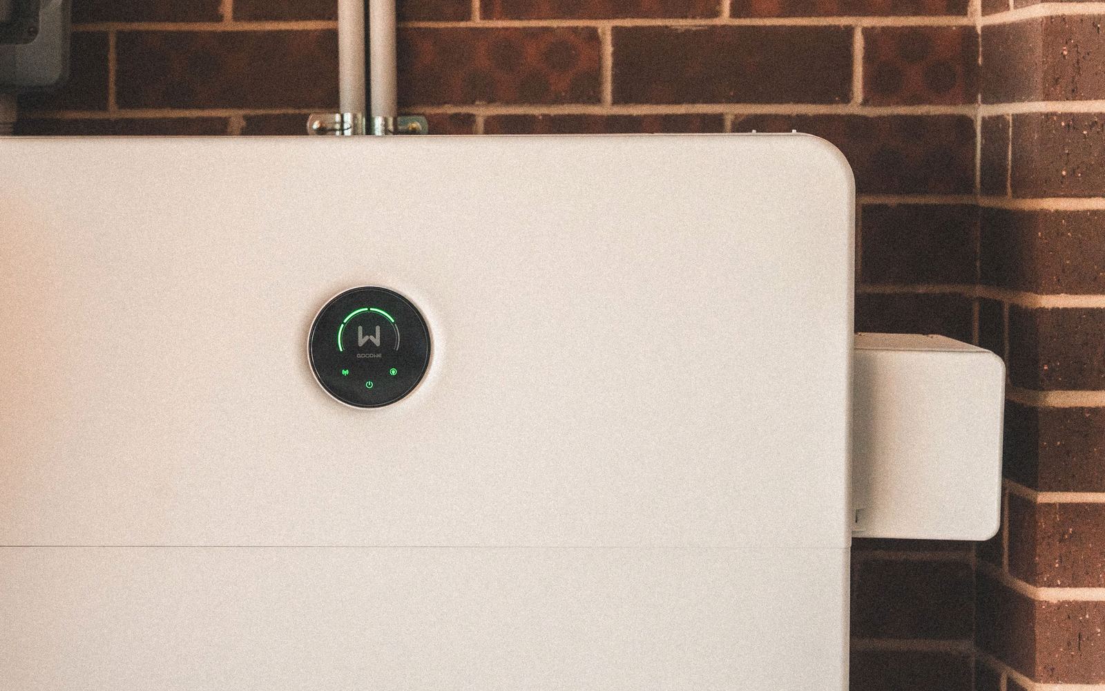 Sleek white home battery mounted on a brick wall